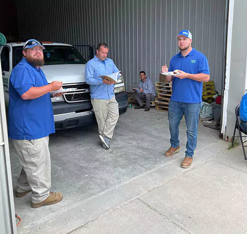 Warweg Employees standing wearing blue color shirts in front of their white car