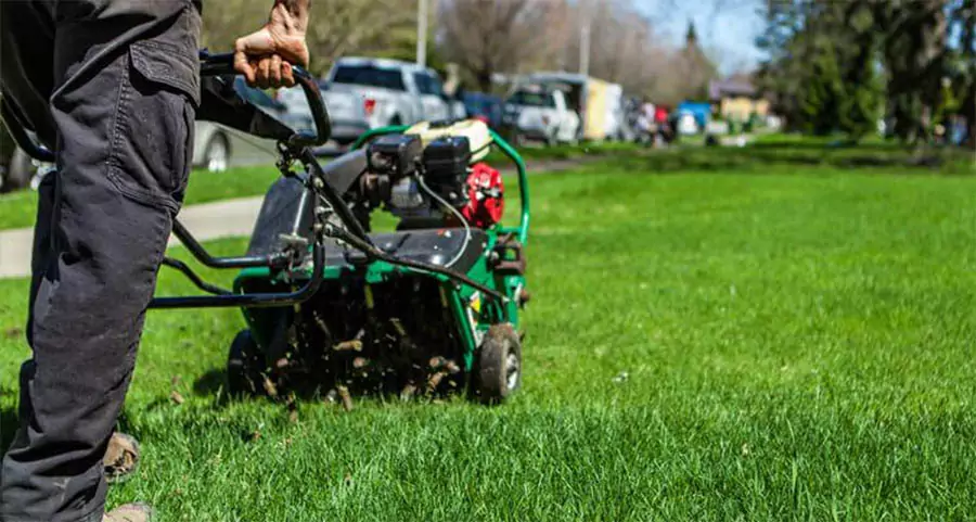 Lawn care worker using a core aerator on a residential yard in Indianapolis during spring lawn aeration service