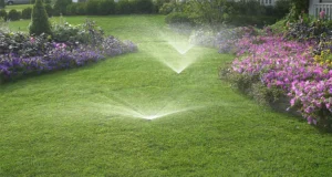 Backyard sprinkler system watering a lush green lawn with flower beds in Indianapolis, installed by local irrigation experts