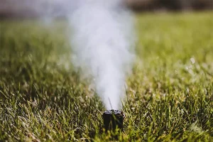 Sprinkler system winterization releasing air to prevent underground pipe bursts on residential lawn in Indianapolis