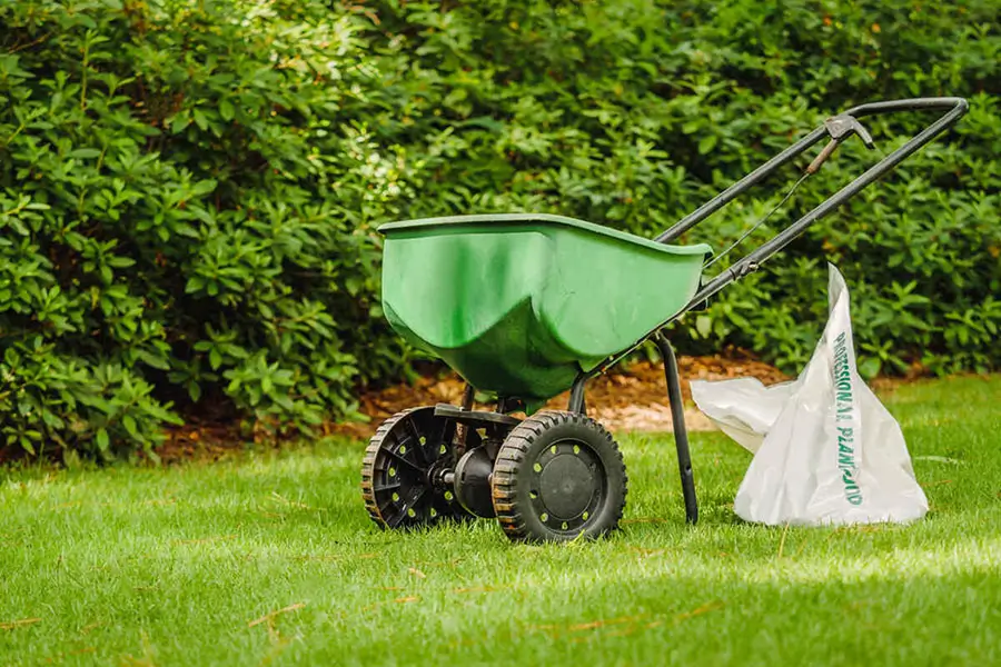 Lawn fertilizer spreader applying weed control treatment on a green Indianapolis lawn during the growing season