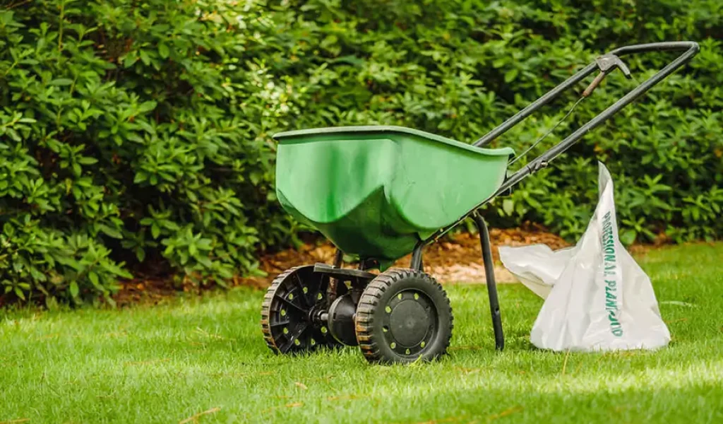 Lawn fertilizer spreader applying weed control treatment on a green Indianapolis lawn during the growing season