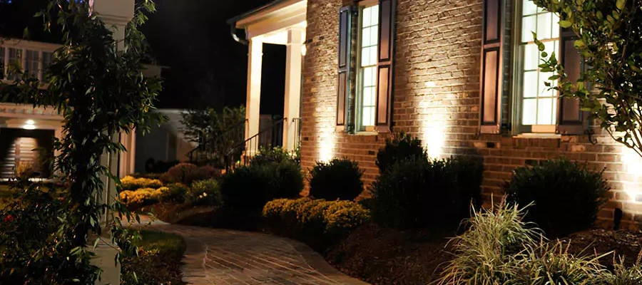Walkway next to brick house with lights shining on the side