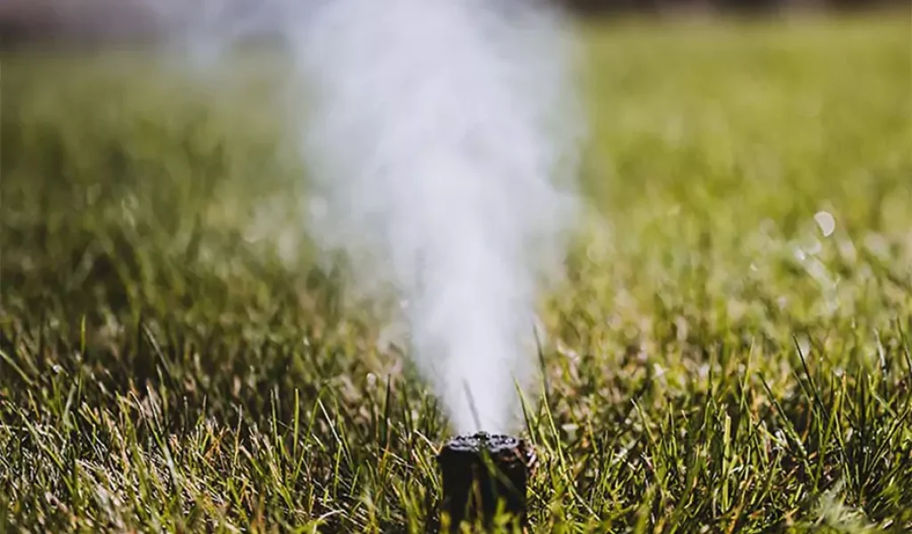 Sprinkler system winterization releasing air to prevent underground pipe bursts on residential lawn in Indianapolis