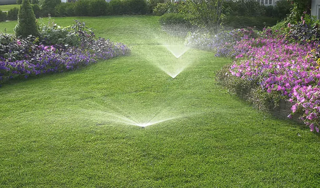 Backyard sprinkler system watering a lush green lawn with flower beds in Indianapolis, installed by local irrigation experts
