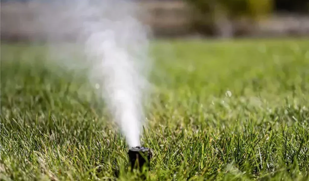 Sprinkler head releasing air during professional blowouts services in Indianapolis lawn to prevent frozen pipes and ensure proper irrigation system maintenance before winter.