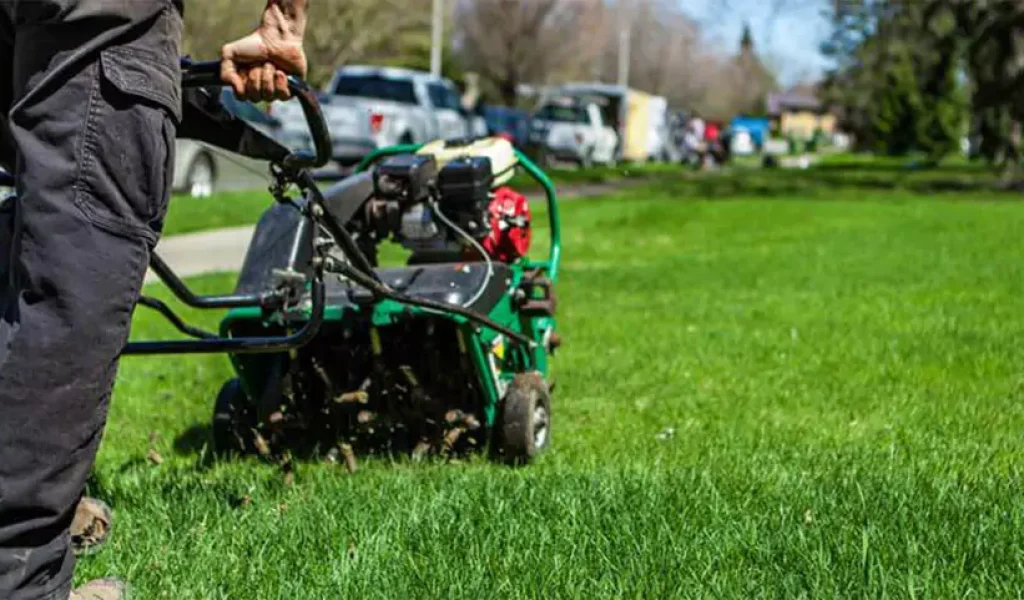 Lawn care worker using a core aerator on a residential yard in Indianapolis during spring lawn aeration service