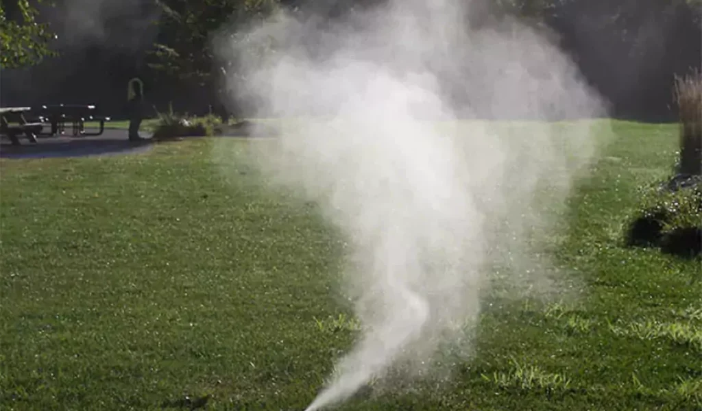 Sprinkler system releasing mist during lawn irrigation in Indianapolis – importance of winterizing irrigation systems to prevent pipe damage.
