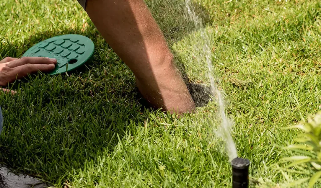 Irrigation technician performing sprinkler system maintenance on a lawn in Indianapolis, IN